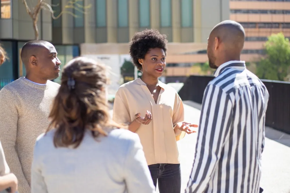 Jeunes professionnels africains échangeant devant un immeuble moderne